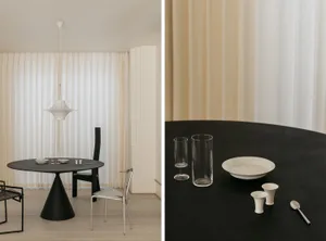 Modern minimalist dining room featuring a sleek black dining table with a concrete base, accompanied by minimalist chairs and