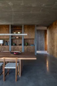 A modern, industrial-style kitchen with wooden furniture and concrete flooring.