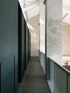 Modern industrial office hallway with concrete walls, herringbone wood floor, and concrete ceiling beams.