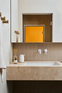 A minimalist bathroom with ceramic tile walls and a stone countertop.