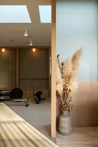 A minimalist fitness room with wood paneling, featuring exercise equipment and a vase of dried grasses.