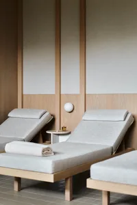 A minimalist spa lounge with fabric-covered recliners and wooden accents.