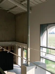 A modern interior space with concrete walls, a concrete staircase, and large windows