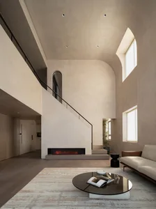 Modern minimalist living room with concrete walls and floor, featuring a sleek fireplace and comfortable seating.
