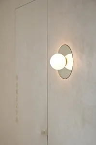 A minimalist wall light fixture embedded in a textured wall, casting a warm glow.