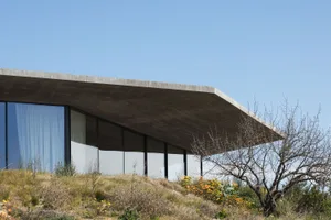 Modern residential building with concrete exterior and large glass windows.