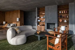 A modern industrial living room featuring a concrete fireplace, wooden shelves, and metal furniture.