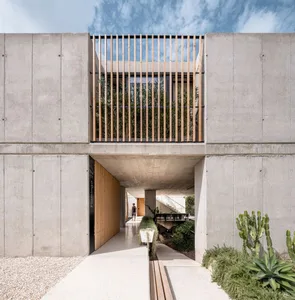Concrete exterior of a modern building with a wooden lattice and green plants
