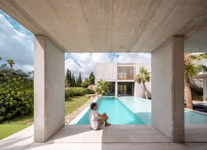 A minimalist backyard featuring a modern house with concrete and glass elements