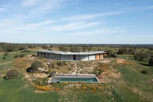 Aerial view of a modern residential house with a flat roof and a swimming pool surrounded by greenery.
