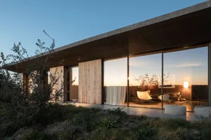 Modern residential exterior featuring glass walls and wooden elements.