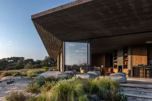 Modern villa with a concrete facade and large windows overlooking a natural landscape.