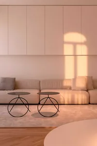 A minimalist living room featuring comfortable seating areas, console tables with unique metal bases, and a sleek, modern des