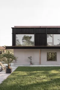 A modern house with a concrete exterior featuring large windows and a minimalist design.