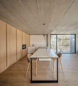A modern kitchen with a concrete counter and wooden stools.