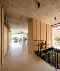 A modern living room featuring a concrete ceiling and wooden panel walls.
