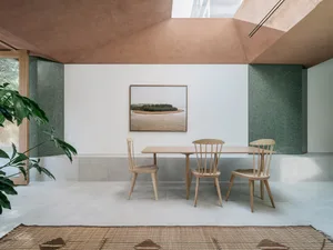 A minimalist interior with a wooden table and ceramic tiles, featuring a light fixture and a framed photograph.