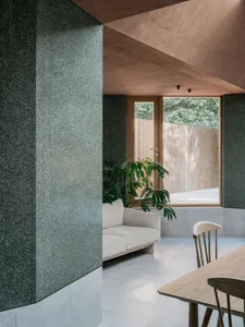 Minimalist living room featuring concrete walls and a large window overlooking greenery.
