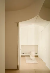 A minimalist bedroom with white furniture, a wooden floor, and a cozy, Riviera-style ambiance.