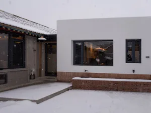 住宅外觀，地面覆雪，設有混凝土步道、磚砌圍牆，以及帶有大窗的牆面。