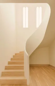 A modern interior staircase with wooden steps and railings, featuring an archway and natural light.