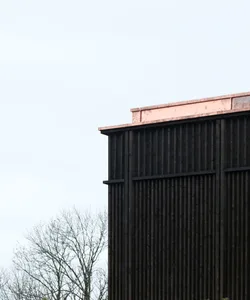 A modern building with dark siding and a copper-colored roof