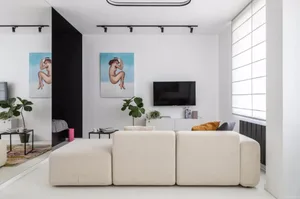 Modern living room featuring a minimalist white and cream color palette, a comfortable beige sectional sofa, and a flat-scree