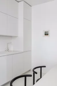 Modern minimalist kitchen featuring sleek white cabinets and minimalist design.