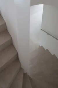 A modern staircase with minimalist design features concrete steps and a white wall.