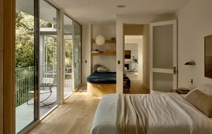 Minimalist bedroom with a white bed and wooden floor.