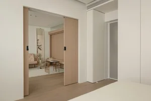A minimalist bedroom featuring wooden furniture and a sliding door.