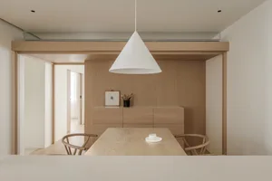 A minimalistic dining room with a wooden table and chairs under a white pendant light.