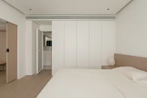 Minimalist white bedroom with wood furniture, clean lines, and simple design elements.