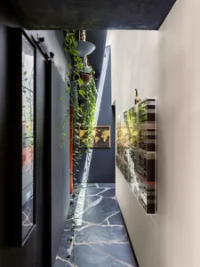 A modern corridor features a black and white marble floor, plant climbing vines, and a world map。