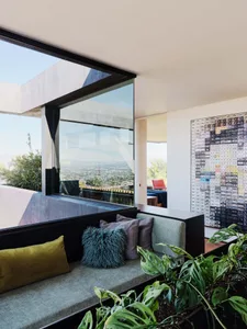 A modern living room featuring a large glass window, concrete floor, and a floor planter with a plant.