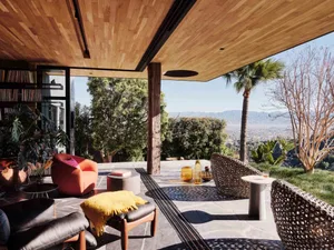 A modern patio featuring stone flooring, wicker furniture, and a scenic outdoor view.