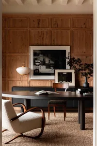 Industrial-style office with wooden walls, a long table, and a comfortable armchair.