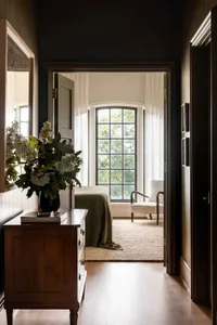 A modern bedroom featuring wooden furniture and textured textiles, with a large window allowing natural light to fill the spa