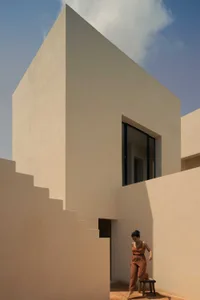 A minimalist, modern building with concrete architecture and a woman stepping down the stairs.