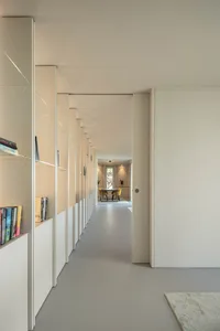 Modern hallway with white walls, glass shelves, and concrete floor