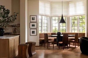 A cozy modern kitchen featuring a built-in bench seating area with a wooden table and chairs, situated under a large bay wind