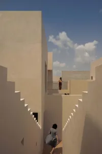 Modern architecture featuring sandstone walls and staircases in a bright, open space.