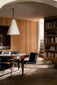 A modern study space featuring wooden walls and a round wooden table with black chairs.