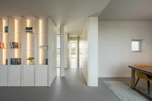 Modern minimalist interior design featuring white walls, white furniture, and contemporary lighting.