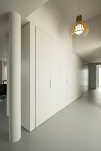 Modern, minimalist storage cupboards in a white room with a wooden light fixture.