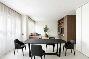 A modern residential dining room featuring contemporary black furniture, white walls, and minimalist decor.