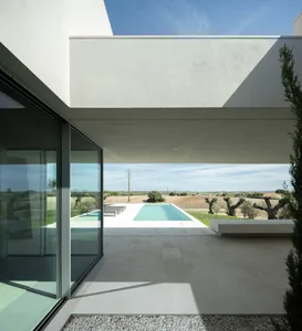 A minimalist modern home with a concrete exterior features a pool with a view of the countryside.
