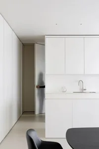 Modern minimalist kitchen with white laminate cabinets and black elements.