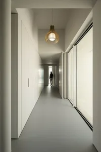 A modern corridor with white plaster walls and wooden pendant light.