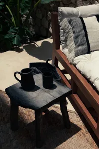 Outdoor wooden furniture with black cups and cushions.